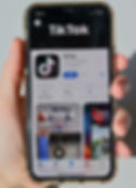 Hand holding a phone with the download option of TikTok app